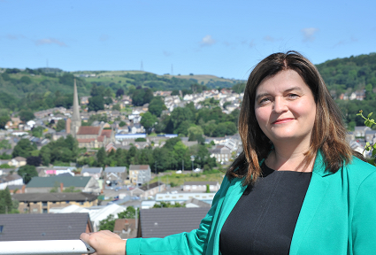 Mae Sioned Williams AS yn sefyll gyda thoeau Pontardawe y tu ôl iddi.