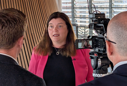 Sioned Williams AS yn cael ei chyfweld gan ddau ddyn â'u cefnau atom. Sioned o flaen camera yn y senedd