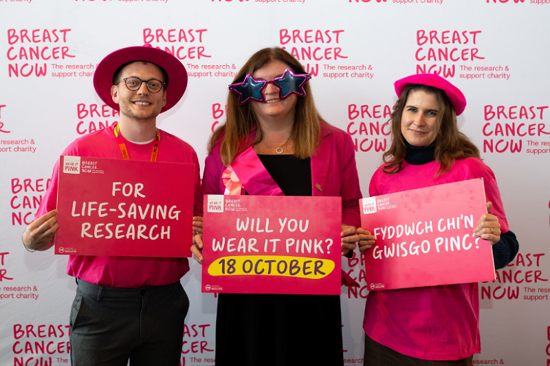 Sioned Williams stands with campaigners from Breast Cancer Now. They are holding a placards that say 