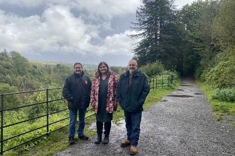 Sioned gyda dau ddyn uwchben y Cwm gydag awyr gymylog yn y cefndir