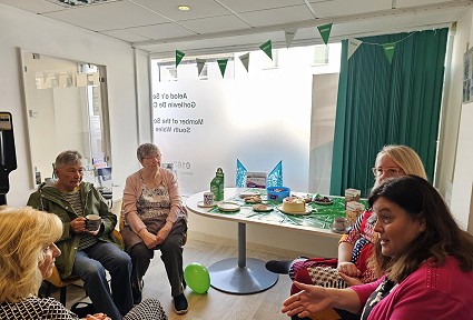 Mae Sioned Williams MS yn mynychu bore coffi er budd Cymorth Canser Macmillan yn fy swyddfa yng Nghastell-nedd wedi'i hamgylchynu gan grŵp o bobl.