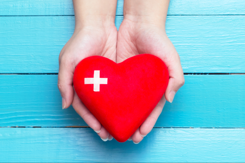 Two hands holding a red heart