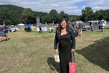 Sioned yn sefyll mewn cae gyda bagiau siopa