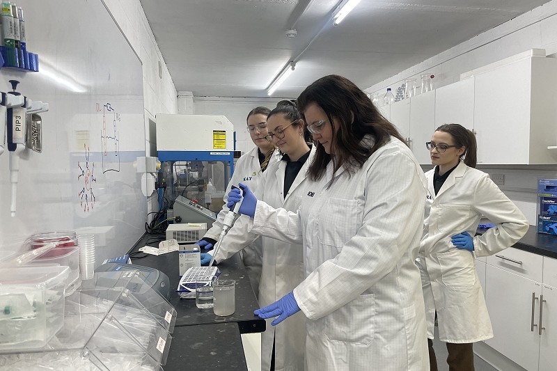 Sioned in a white coat using a pipet