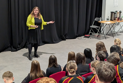 Sioned Williams ar y llwyfan yn siarad ag Ysgol Cwm Brombil