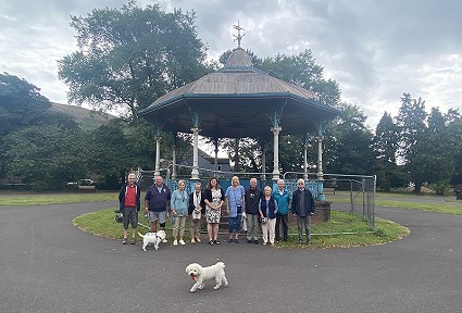 grŵp o bobl yn sefyll yn y parc gyda 3 chi gwyn