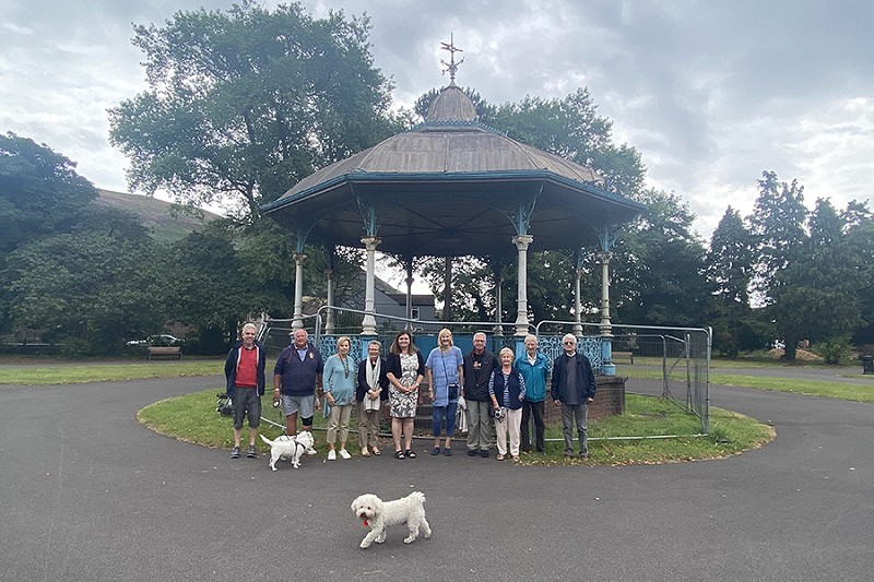 grŵp o bobl yn sefyll yn y parc gyda 3 chi gwyn