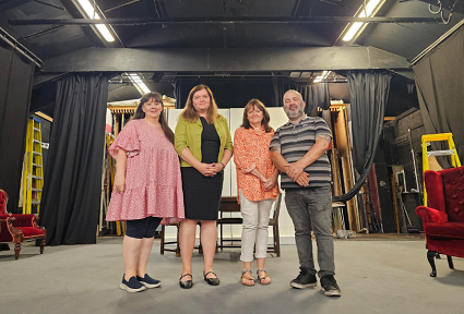 Sioned Williams yn sefyll ar lwyfan theatr gyda thri pherson arall