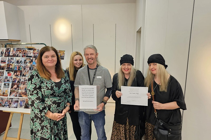 Sioned Williams MS gyda grŵp o bobl yn dal tystysgrifau gwobrwyo i staff M&S