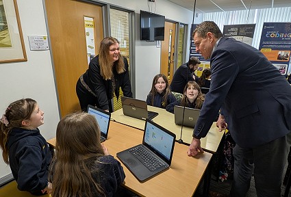 Mae Sioned Williams a Rhun ap Iorwerth wrth fwrdd gyda phlant mewn dosbarth Technocamps