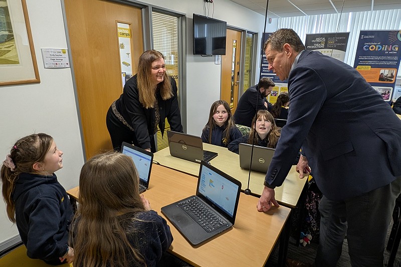 Mae Sioned Williams a Rhun ap Iorwerth wrth fwrdd gyda phlant mewn dosbarth Technocamps