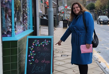 Sioned in a blue coat on a high street pointing at a 