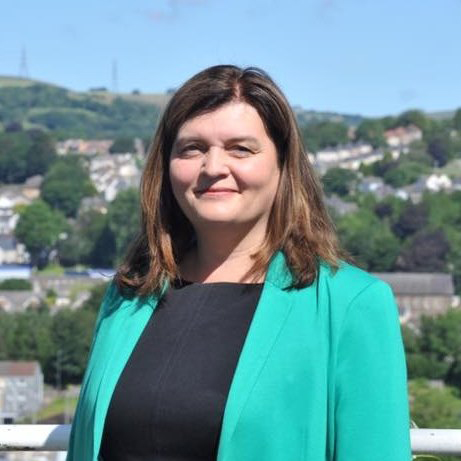 A woman smiling wearing a green suit jacket outside