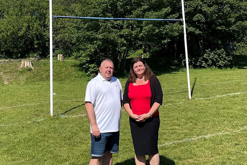 Sioned Williams and Jamie Watkins standing by some rugby pots
