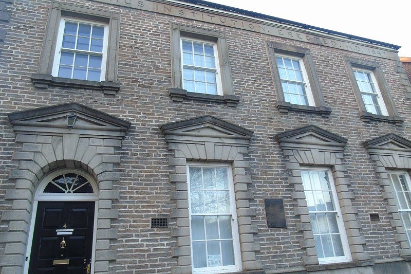 Plaque outside Neath Mechanics Institute - grey building