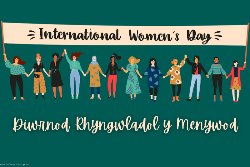 Petryal gwyrdd tywyll gyda graffig o lawer o ferched gwahanol yn y canol. Maen nhw'n sefyll o dan faner sy'n dweud 