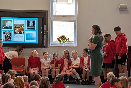 Sioned yn siarad â disgyblion ysgol mewn gwasanaeth