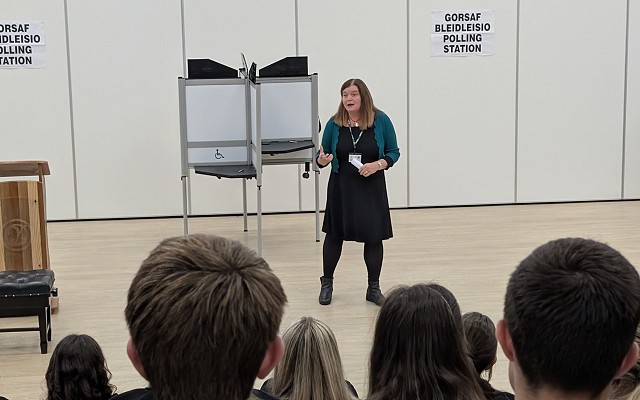 Sioned speaking to pupils in an auditorium