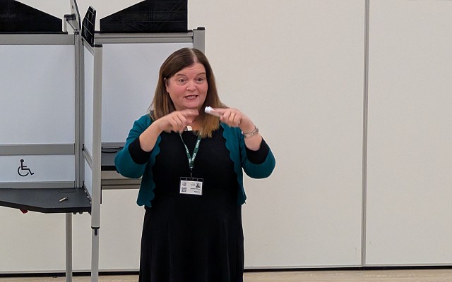 Sioned speaking to pupils in an auditorium